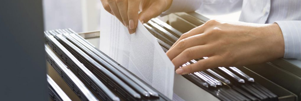 woman handling files inside a file cabinet while using blockchain at the same time, illustrating blockchain-based file storage